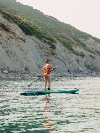 July 30, 2022. Dalaman, Turkey. Woman rowing on stand up paddle board at sea with mountain landscape.のeditorial素材