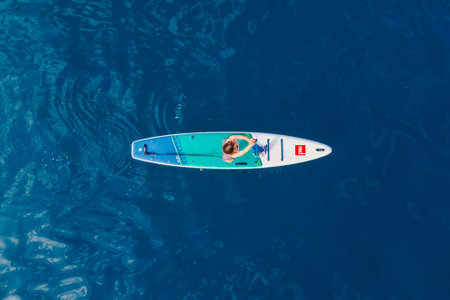 June 21, 2022. Dalaman, Turkey. Aerial view of female on stand up paddle board at sea. Woman on Red paddle sup board in ocean.のeditorial素材