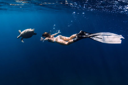 Lady with fins snorkeling underwater with turtle in ocean. Swimming with sea turtle.の写真素材