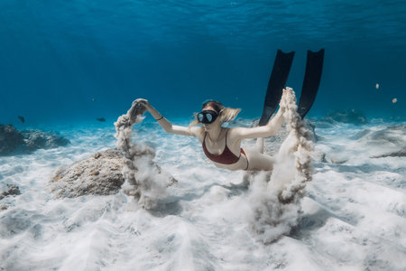 Freediver swims underwater and playing with sand. Freediving with attractive woman in tropical blue oceanの写真素材