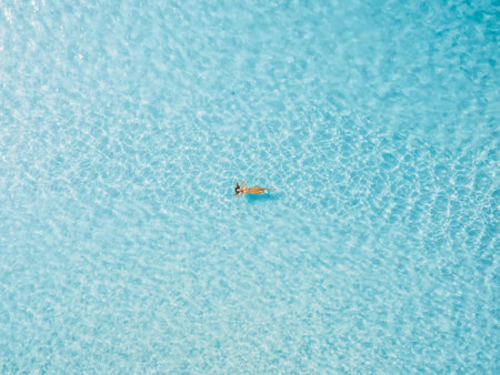 Woman floating and relaxing in tropical blue sea. Aerial view, top view.