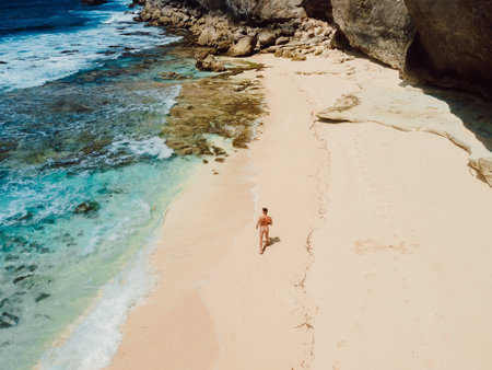 Naked handsome man sunbathing at paradise ocean beach. Aerial viewの写真素材
