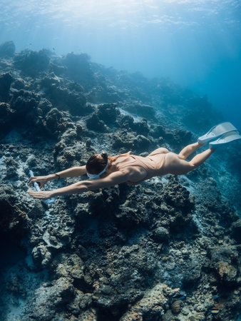Woman freediver training on deep in blue ocean. Female freediver swims underwaterの写真素材