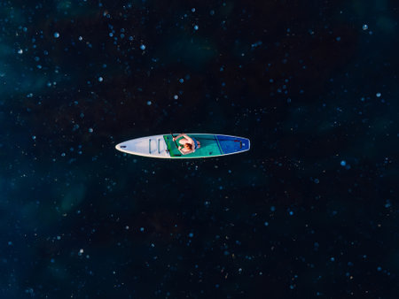 Woman on stand up paddle board at blue sea with a lot of jelly fish. Traveling on sup board in sea. Aerial viewの写真素材