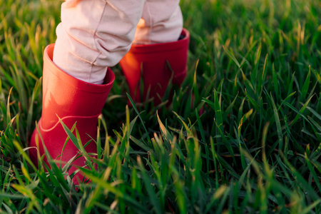 Child girl legs in boots in the field. Sunset light
