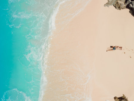 Handsome man sunbathing at tropical ocean beach. Aerial view