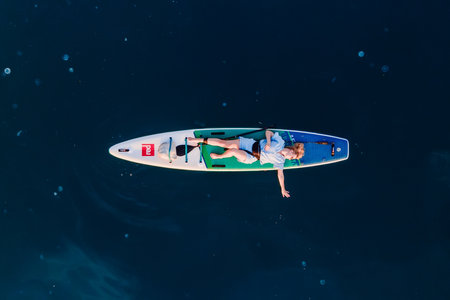 April 28, 2023. Antalya, Turkey. Woman relaxing on stand up paddle board at blue sea. Traveling on...