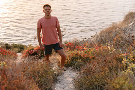 Handsome man on the ocean coastline with warm sun light.の写真素材