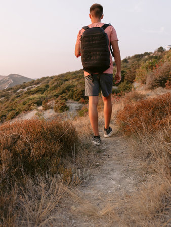 Hiker man with backpack walk on mountain sea coastline with warm sun light.の写真素材