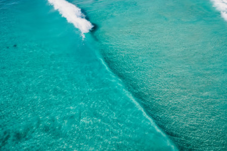 Top view of turquoise ocean and surfing waves, drone view