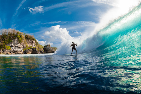 August 08, 2024. Bali, Indonesia. Surfer ride on surfboard at barrel wave. Professional surfing in...
