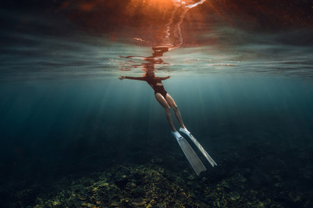 Woman free diver relaxing on surface of ocean after diving. Woman freediving on morning with warm sun lightの写真素材