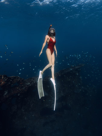 Woman freediver dives in blue ocean on wreck ship.の写真素材