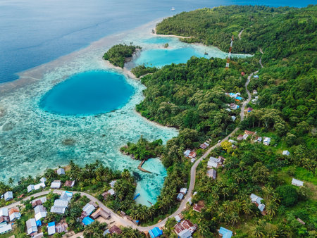 Sea coastline with blue hole in big lagoon and village, scenic landscape in Indonesia. Aerial viewの写真素材