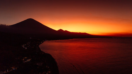 Drone view panorama of coastline with silhouette of volcano and sunset with quiet sea in Bali.の写真素材