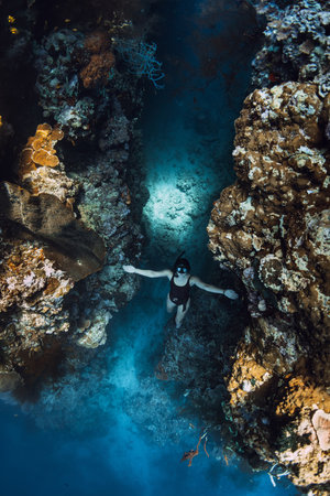 Woman freediver emerges from the underwater cave in tropical sea on Menjangan island, Bali.