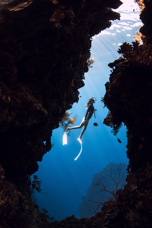 Woman freediver diving in underwater cave on Menjangan island, Bali.の写真素材