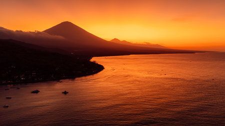 Drone view panorama of coastline with silhouette of volcano and sunset with quiet sea in Bali.の写真素材
