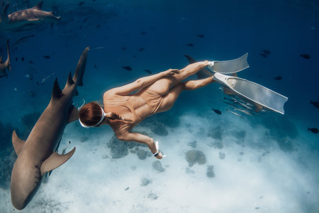 Stunning underwater view of a freediver woman swimming with nurse sharks in ocean watersの写真素材