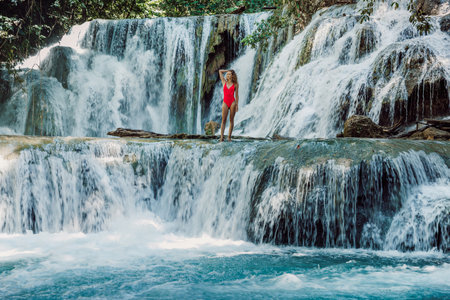 Woman on scenic cascade waterfalls with blue water in Luwuk, Central Sulawesiの写真素材