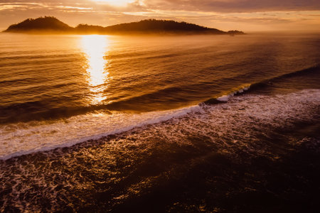 Scenic ocean landscape with warm sunrise and silhouette of Campeche island in Florianopolis, Brazil
