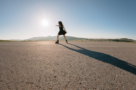 Young woman roller skating on road, leisure activity in summerの写真素材