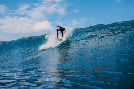 Surfer woman on surfboard during tropical surfing. Surfer girl pop up on ocean wave