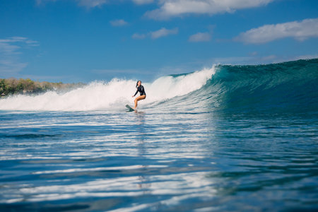 Female surfer riding a perfect blue wave on a sunny day and the beauty of surfing in ocean.の写真素材