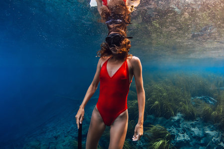 Beautiful woman swims underwater in the blue lake.の写真素材