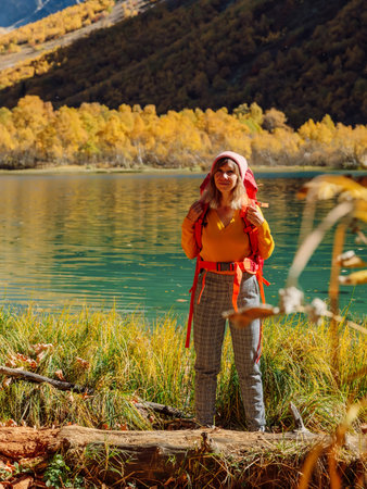 Cheerful hiker woman nearly crystal lake in autumnal mountains.の写真素材