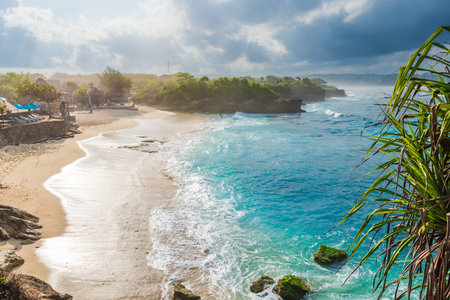 Tropical paradise beach with ocean and cloudy sky with sun rays in Lembongan islandの写真素材