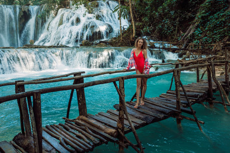 Beautiful traveller woman on bridge at cascade waterfalls with turquoise water in Central Sulawesiの写真素材