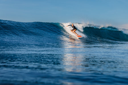 Woman surfer riding on a perfect glassy wave on a sunny day. Surfing in ocean.