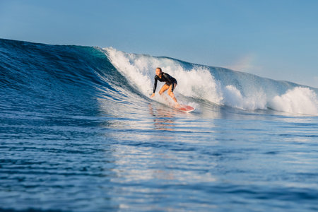 Female surfer riding a perfect blue wave on a sunny day and the beauty of surfing in ocean.の写真素材