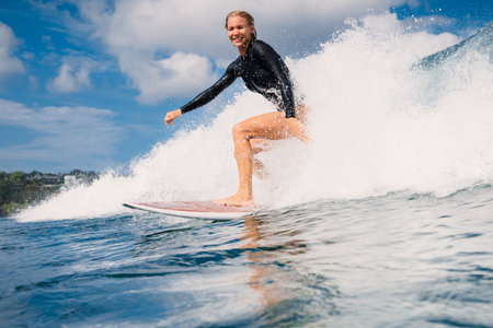 Female surfer riding a perfect breaking wave on a sunny day