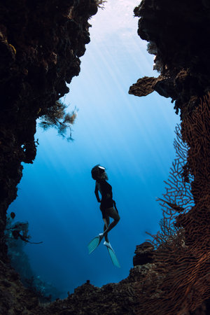 Woman dives in deep underwater cave on Menjangan island, Bali. Freediver swims in caveの写真素材