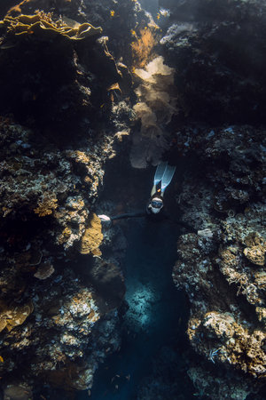 Female freediver emerges from the underwater cave in oceanの写真素材
