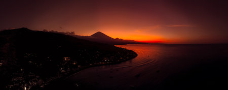 Drone view panorama of coastline with silhouette of volcano at dusk in Bali.の写真素材