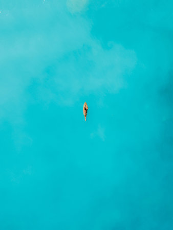 Surfer on surfboard in blue ocean. Drone view of surferの写真素材
