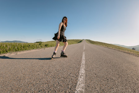 Young attractive woman roller skating on road, summer leisure activityの写真素材