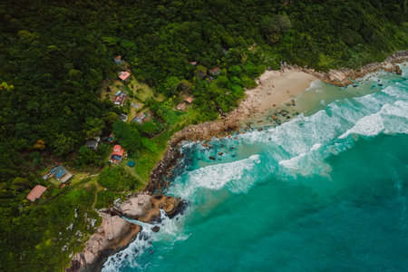Aerial view of a secluded ocean beach, surrounded by lush forest, rocky coastline in Brazil.の写真素材