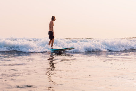 Surfer on longboard rides on fun ocean wave in Baliの写真素材