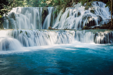 Scenic cascade waterfall with blue water in tropical jungle, long exposure
