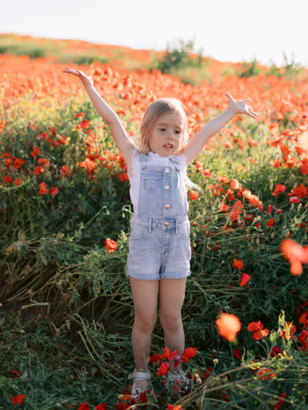 Little girl in a poppy field, throws flowers and enjoying a sunny summer dayの写真素材