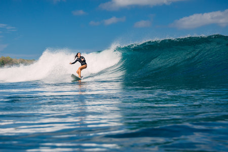 Woman surfer ride on surfboard on breaking ocean wave on a sunny dayの写真素材