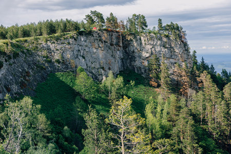 Rocky cliff mountains surrounded by lush forest in summer