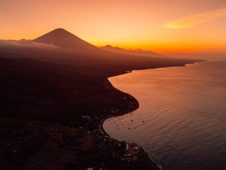 Drone view scenic panorama of coastline with silhouette of volcano and sunset with quiet ocean in Bali.の写真素材