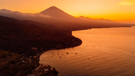 Drone view scenic panorama of coastline with silhouette of volcano and sunset with ocean in Bali.の写真素材