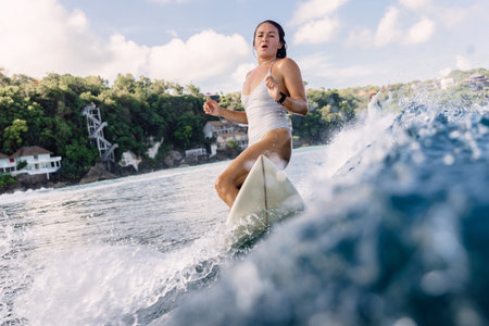 Female surfer on surfboard during surfing. Surfer woman and ocean waveの写真素材