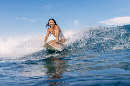 Female surfer on surfboard during surfing. Smiling surfer woman and ocean wave